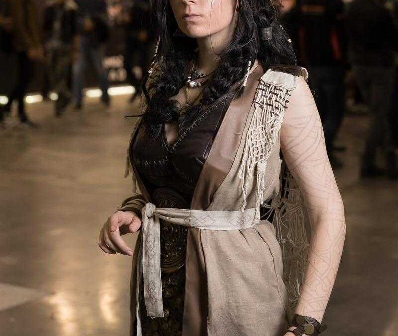 Девушка с черными волнистыми волосами в костюме на фоне толпы