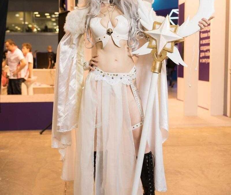 Косплей героини с длинными светлыми волосами в белом наряде со staff