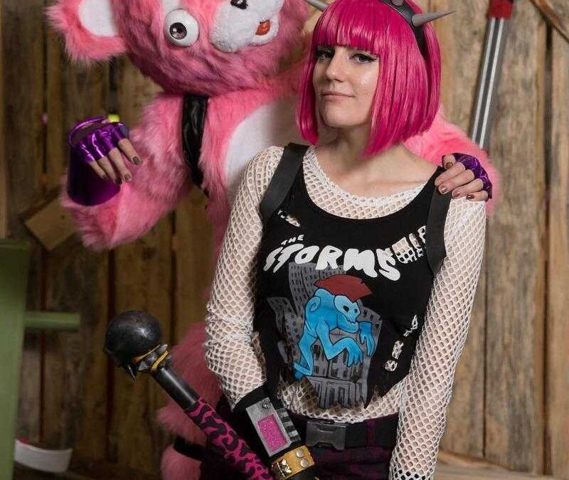 Косплей персонажа из игры с яркой розовой прической и шипами на головном уборе