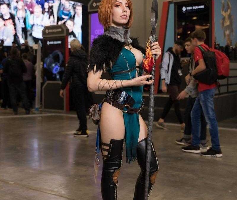 Косплей на персонажа из игры в тематическом костюме с огнем и посохом на выставке ИгроМир 2018