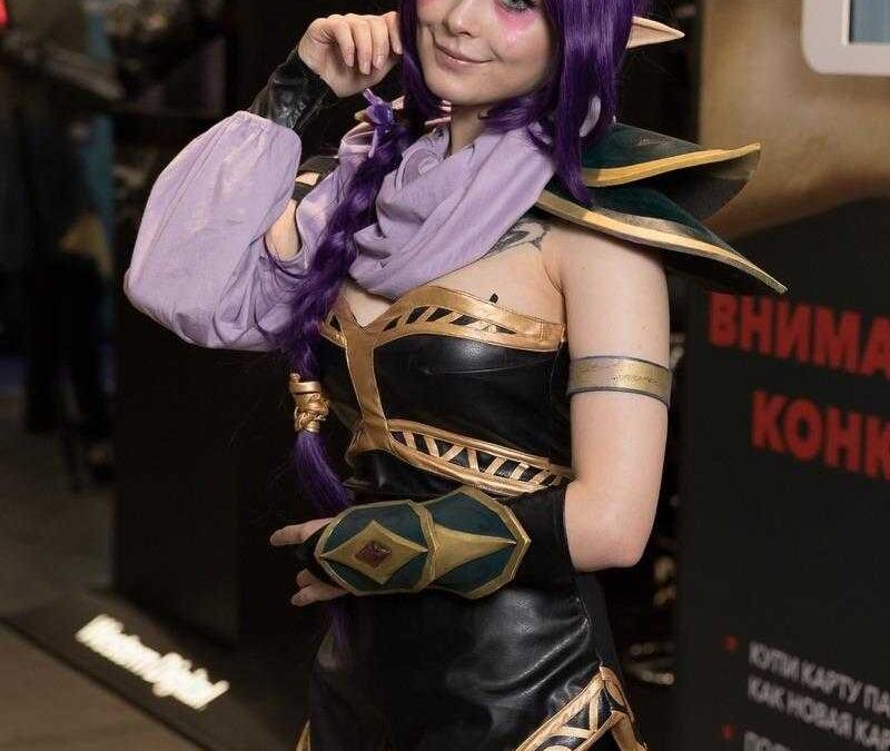Косплей героини из игры с фиолетовыми волосами и рукавом в стиле магии