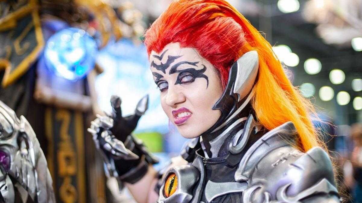 Косплей девушки с ярко-оранжевыми и красными волосами в броне из игры Overwatch
