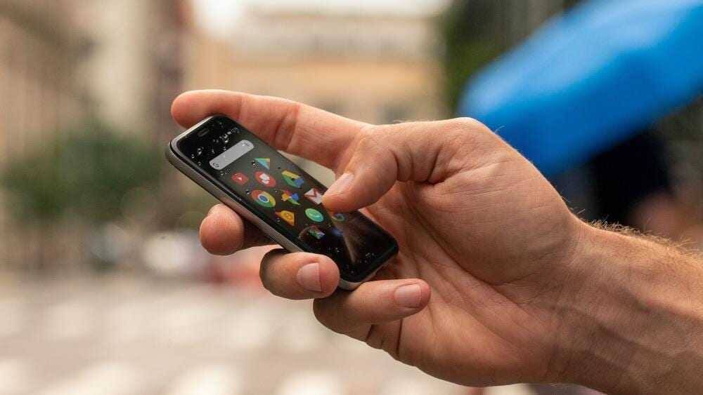 Мужчина держит смартфон Palm с ярким дисплеем