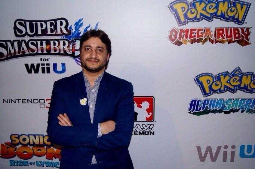 Фотография мужчины в синем костюме у стенда с логотипами Pokémon и Wii U
