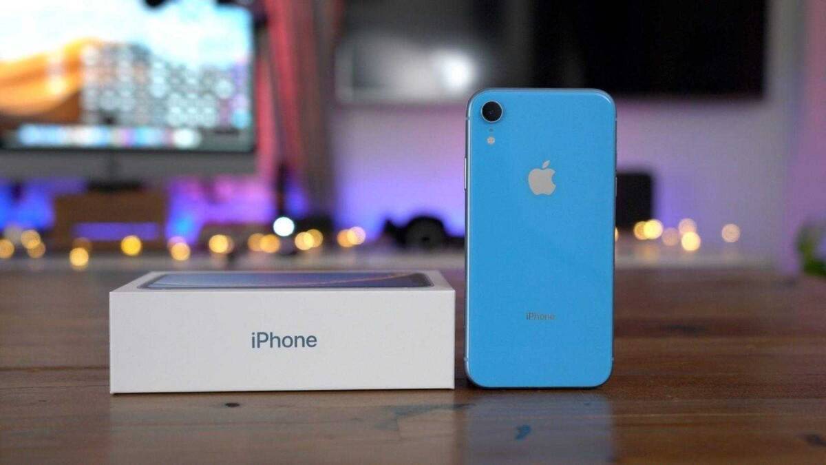 Синий iPhone XR рядом с коробкой на деревянном столе
