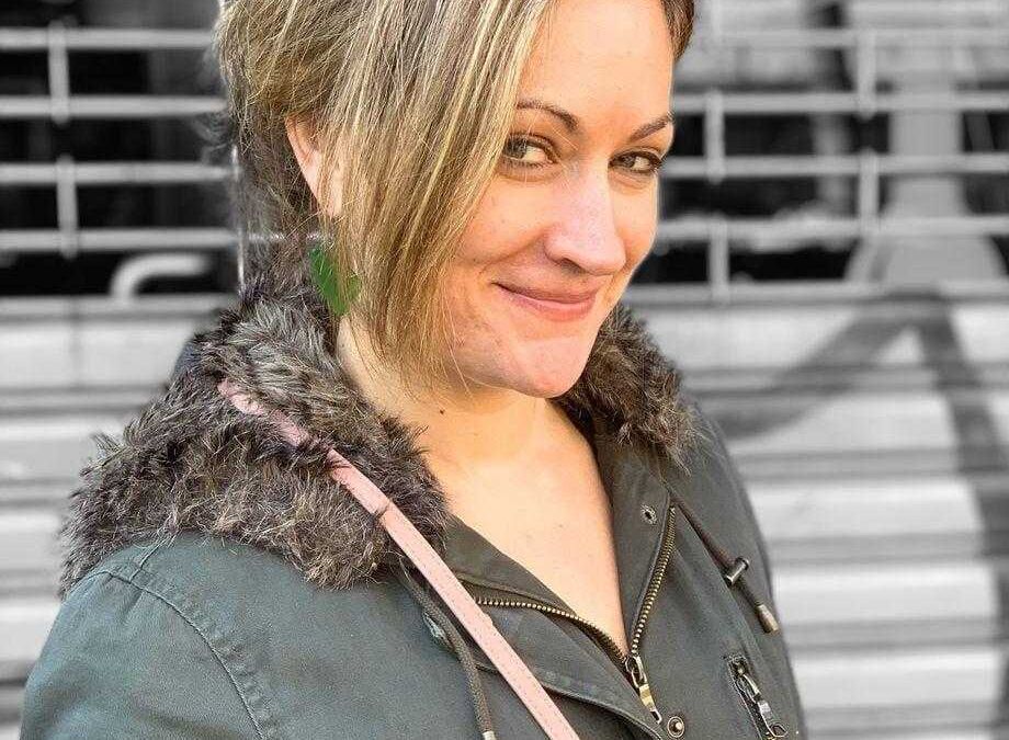 Женщина с короткой стрижкой на улице в серой куртке с меховой отделкой