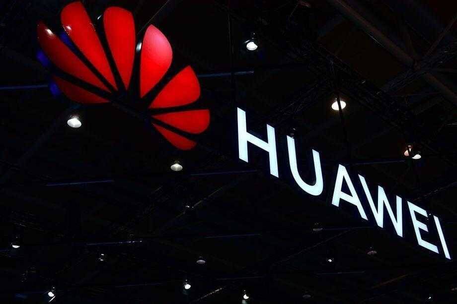 Вывеска компании Huawei с белым логотипом и названием на тёмном фоне
