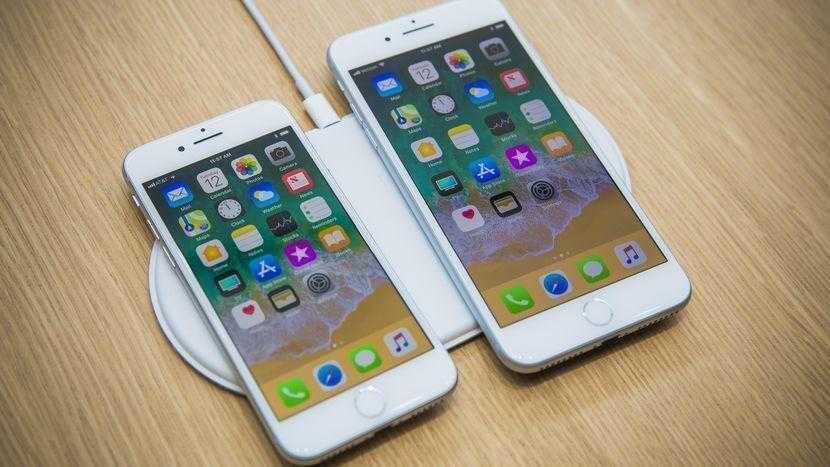 Два белых iPhone на беспроводной зарядной платформе