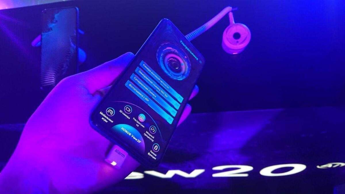Honor показала смартфон View 20 в России 8 Рука держит смартфон Honor View 20 в руке На экране отображается интерфейс камеры и настройки В фоновом изображении видна синяя подсветка и название Honor View 20