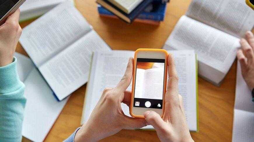 Снимок телефона сзади, показывает открытую страницу книги в фокусе