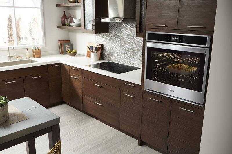 Современная кухня с встроенной духовкой Whirlpool на фоне шкафов и стола