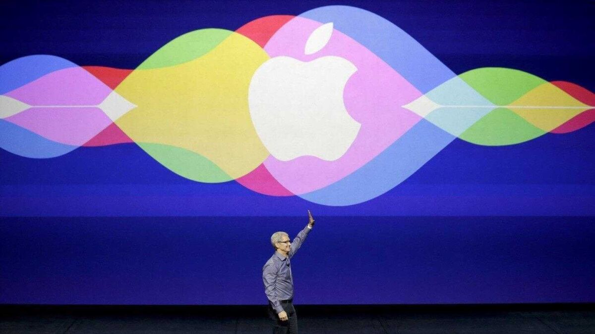 Мужчина в очках и рубашке показывает на экран с логотипом Apple