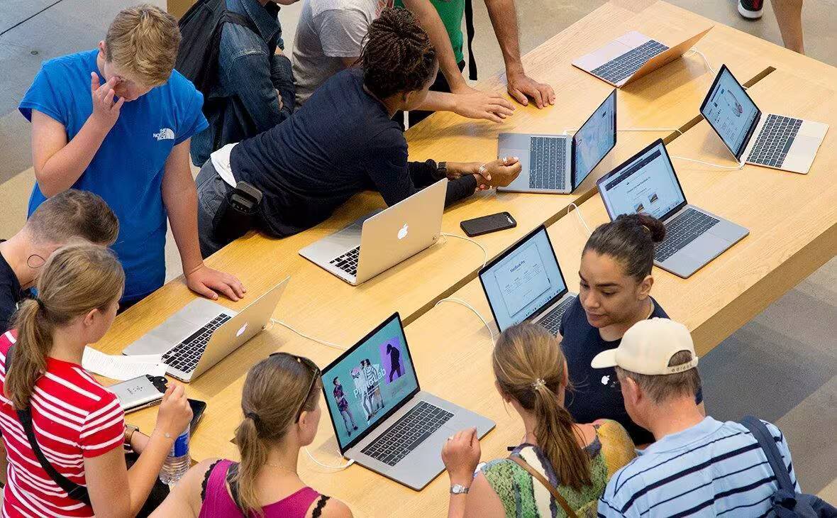 Люди собираются вокруг ноутбуков Apple на столе