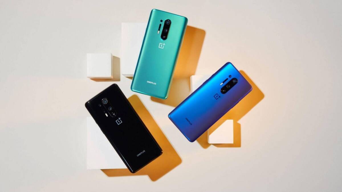 Три смартфона OnePlus 8 и OnePlus 8 Pro на белой подставке в ярком освещении