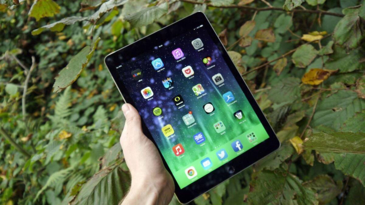 Планшет iPad Air на фоне зелёных листьев в руках