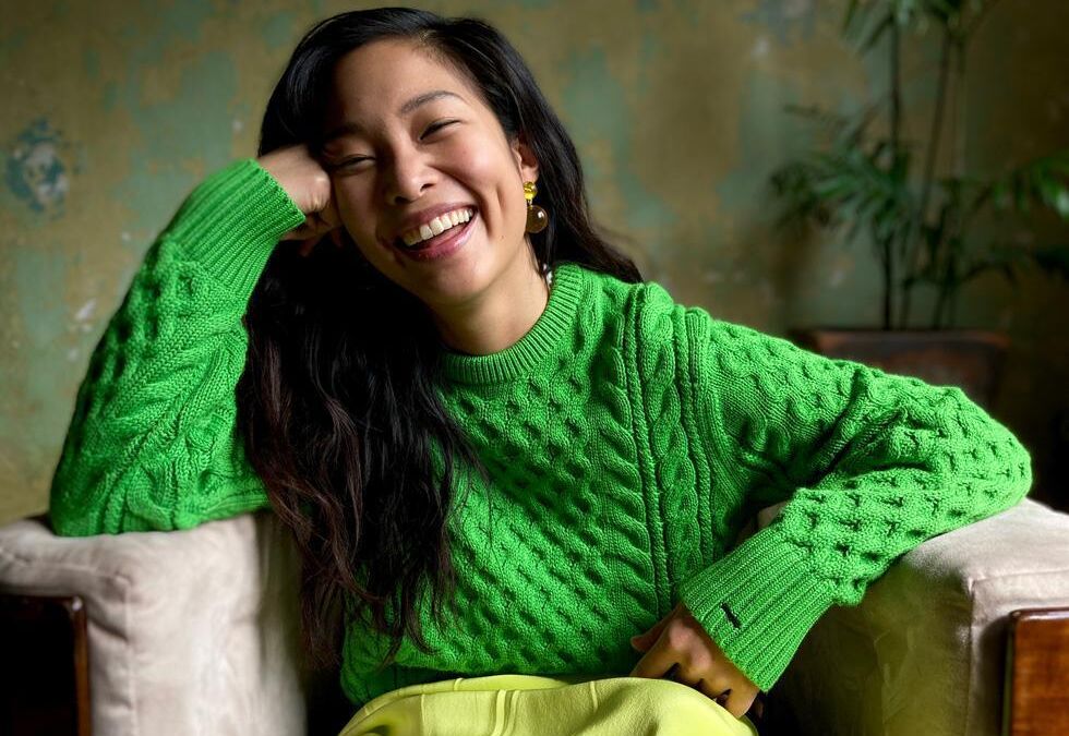 Женщина в ярко-зеленом свитере улыбается на фото