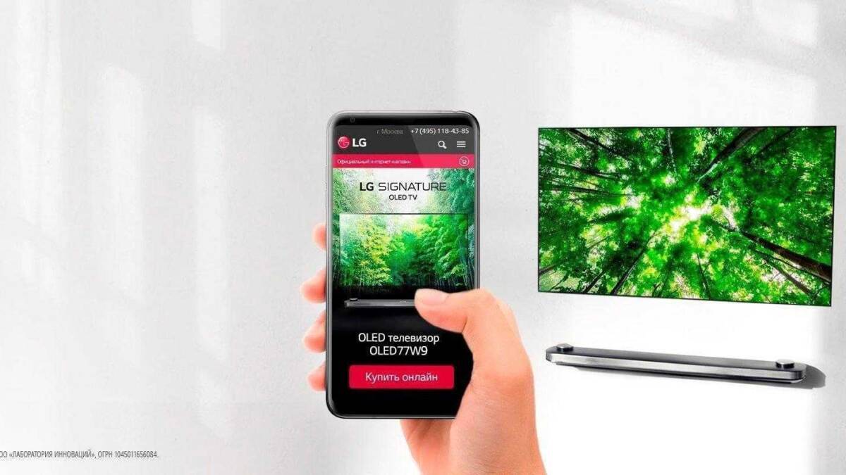 Рука держит смартфон LG с отображением сайта модели OLED77W9