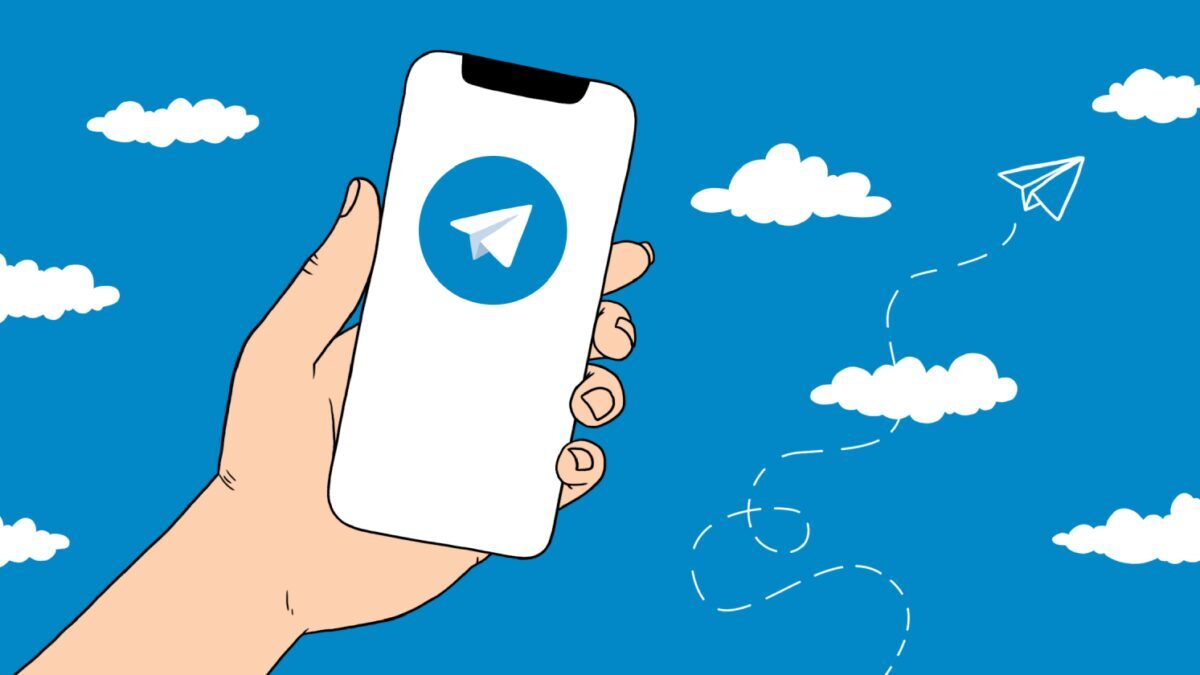 Рука держит смартфон с логотипом Telegram на экране