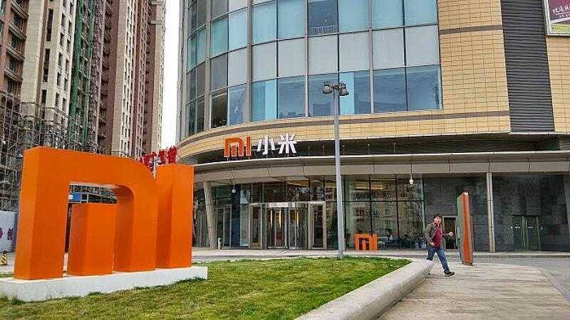 Здание с логотипом Xiaomi и рекламным щитом на улице