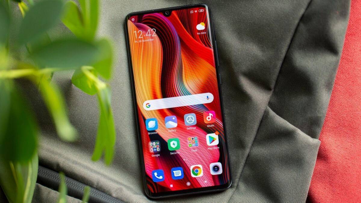 Смартфон Xiaomi на фоне чёрной ткани и зелени