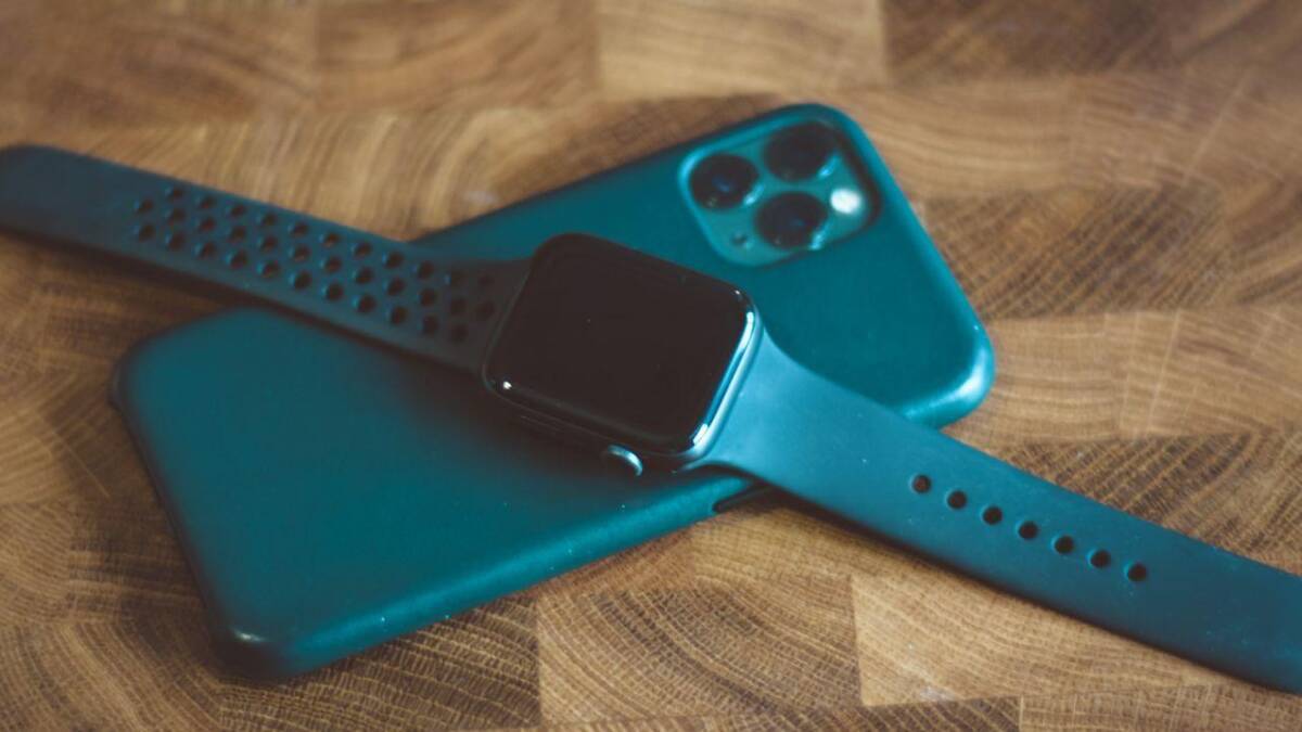 Умные часы Apple Watch и смартфон iPhone на деревянном столе