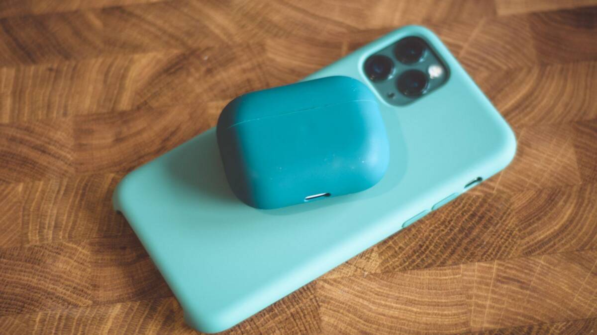 Тёмно-голубые наушники AirPods на синем айфоне на деревянном столе