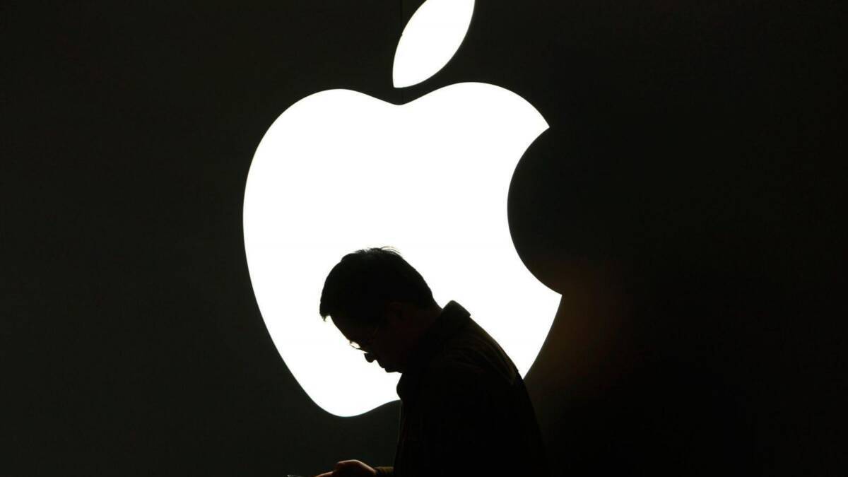 Силуэт человека возле крупного логотипа Apple и iPhone 12