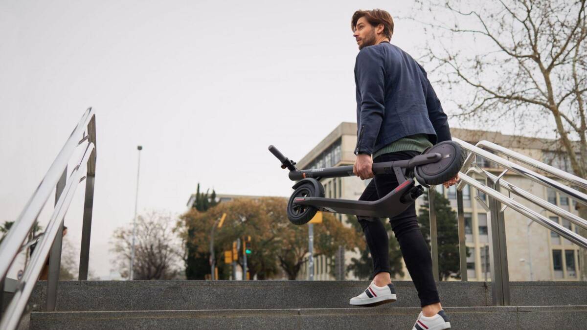 Мужчина с электросамокатом Segway KickScooter E22 на улице