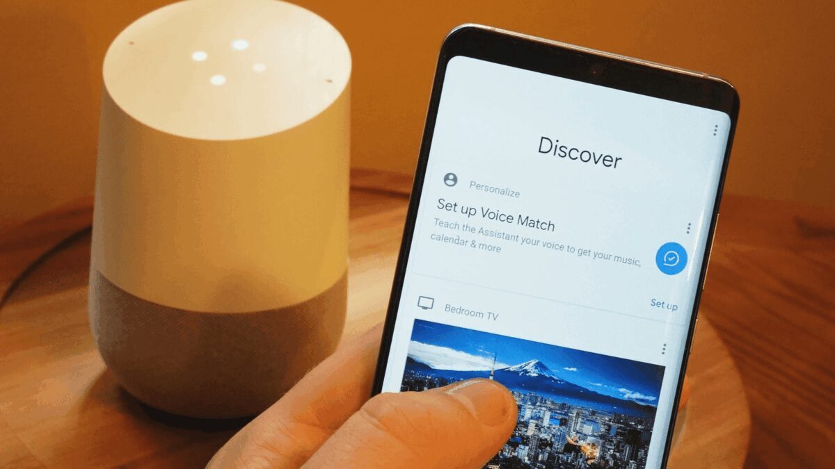 Рука держит смартфон с интерфейсом Google Assistant
