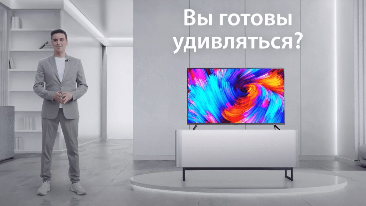 Человек в светлом костюме рядом с телевизором Xiaomi Mi TV
