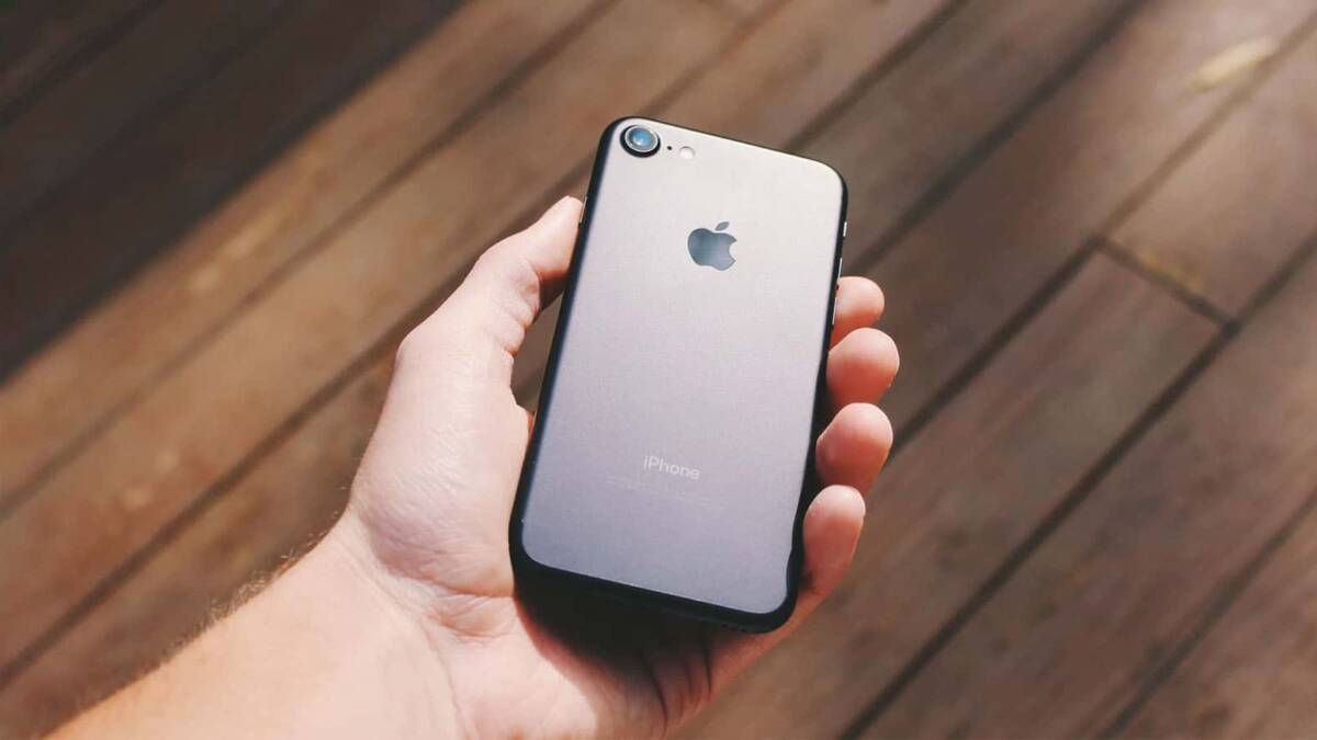 ФБР разблокировало iPhone без помощи Apple 4 Рука держит iPhone с задней стороны на деревянном полу