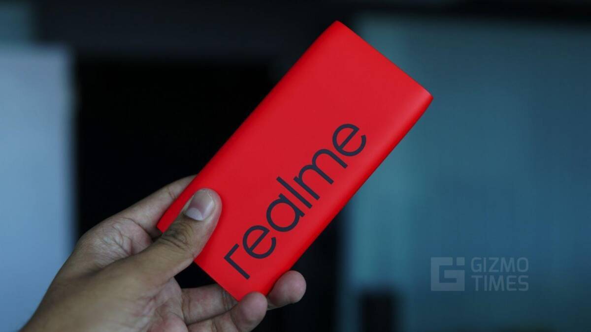 Ручка в руке с яркой красной упаковкой Realme