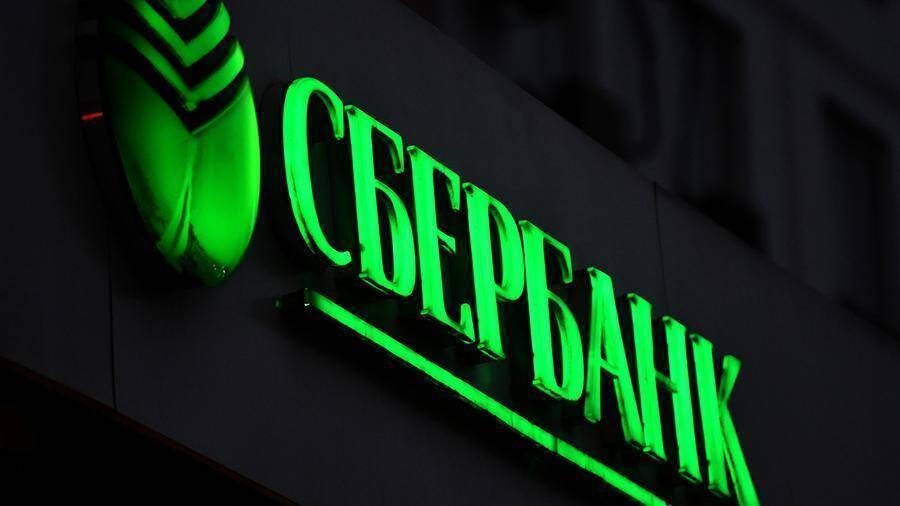 Изображение освещенного светодиодного вывески Сбербанк на темной стене