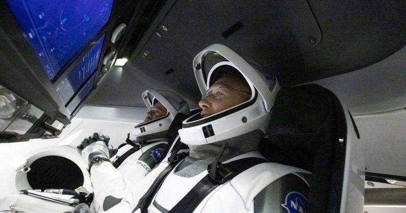 Два астронавта в скафандрах внутри кабины космического корабля NASA
