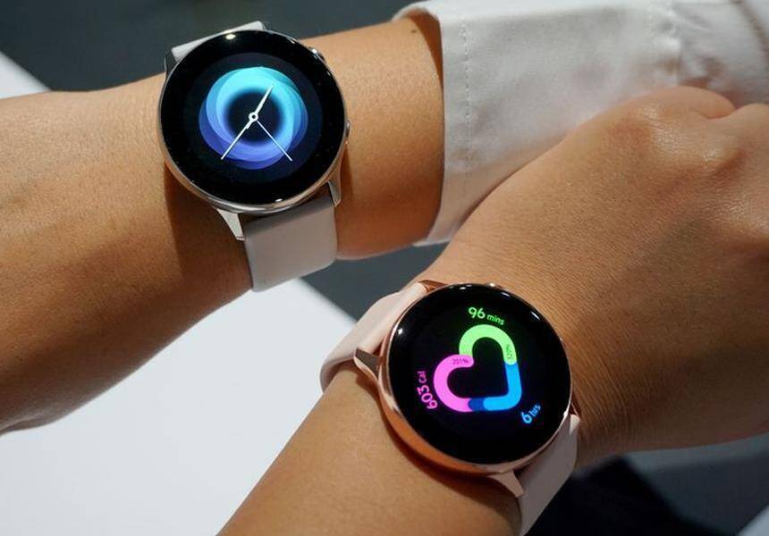 Два умных часах Samsung Galaxy Watch 3 на запястьях пользователей отображают интерфейс