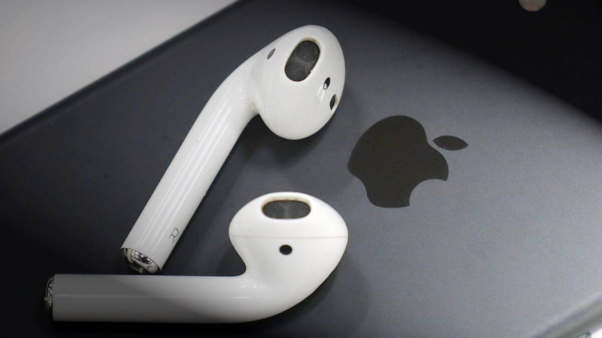 Беспроводные наушники Apple AirPods на чёрной поверхности