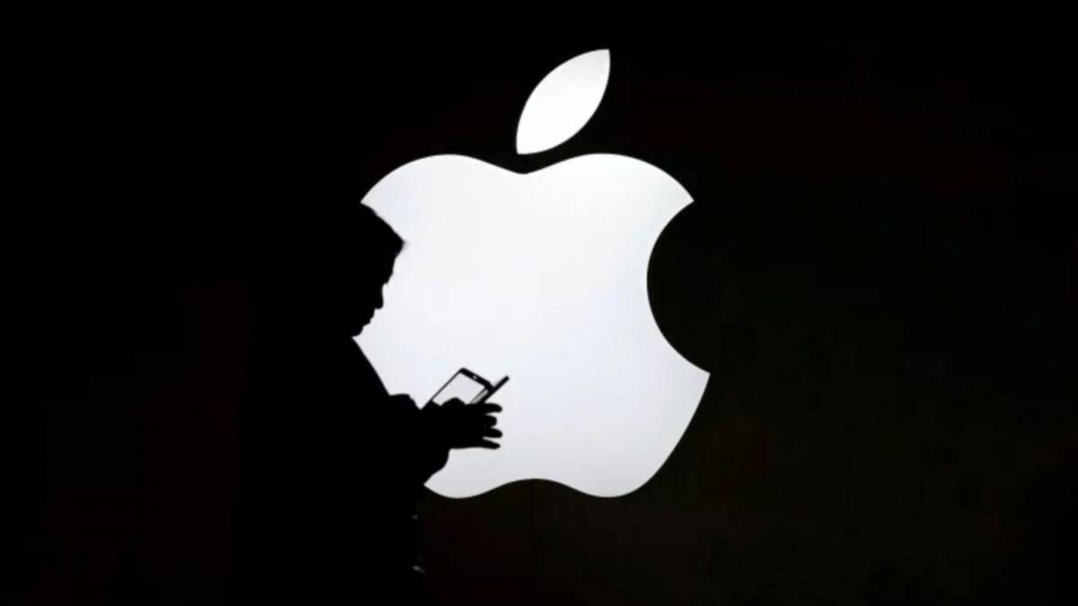силуэт человека с телефоном перед большим логотипом Apple