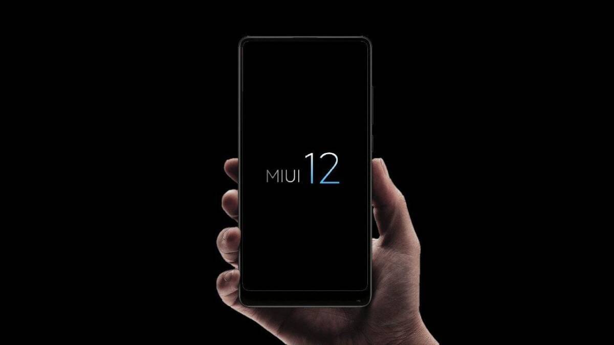Мобильный телефон Xiaomi с экраном MIUI 12 в руке черный фон