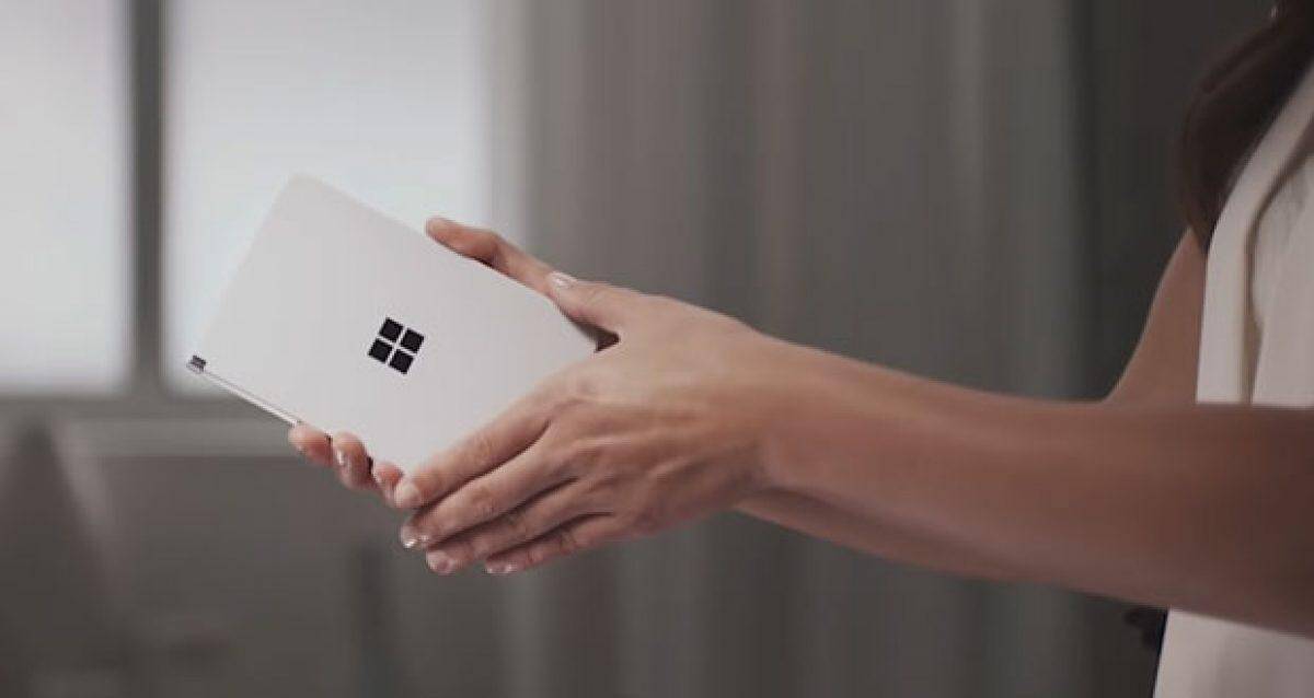 Человек держит белый планшет Microsoft Surface Duo