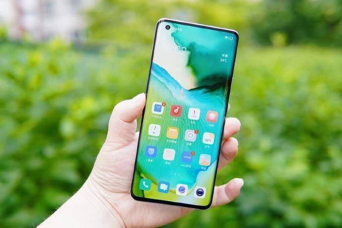 Смартфон на руке на фоне зелени дисплей с иконками приложений