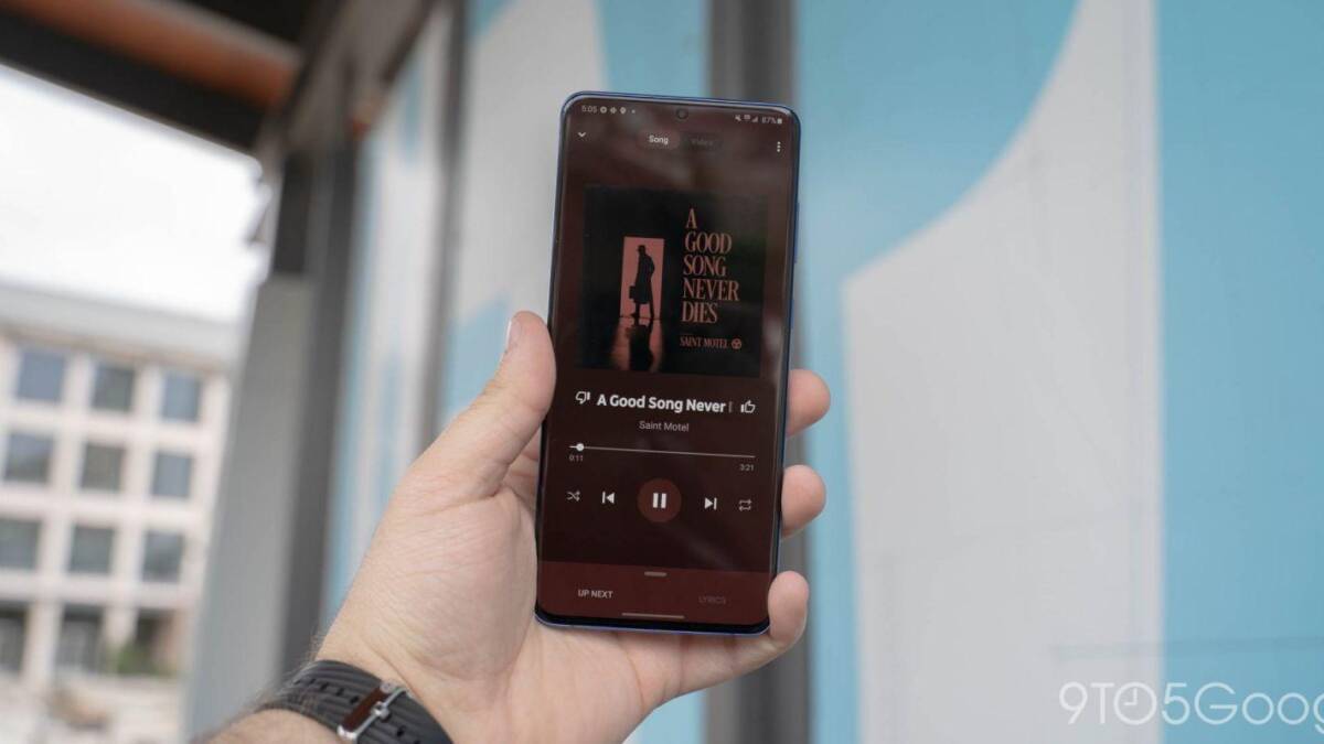 Экран смартфона с интерфейсом YouTube Music в руке человека