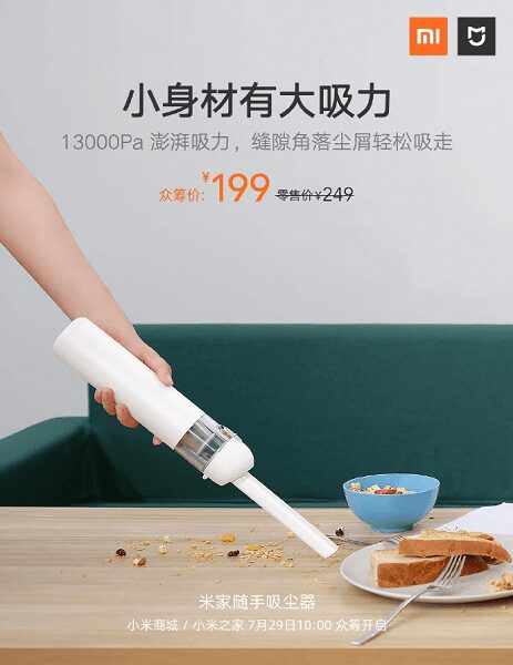 Маленький пылесос Xiaomi для сухой уборки держит руку и пятна на столе