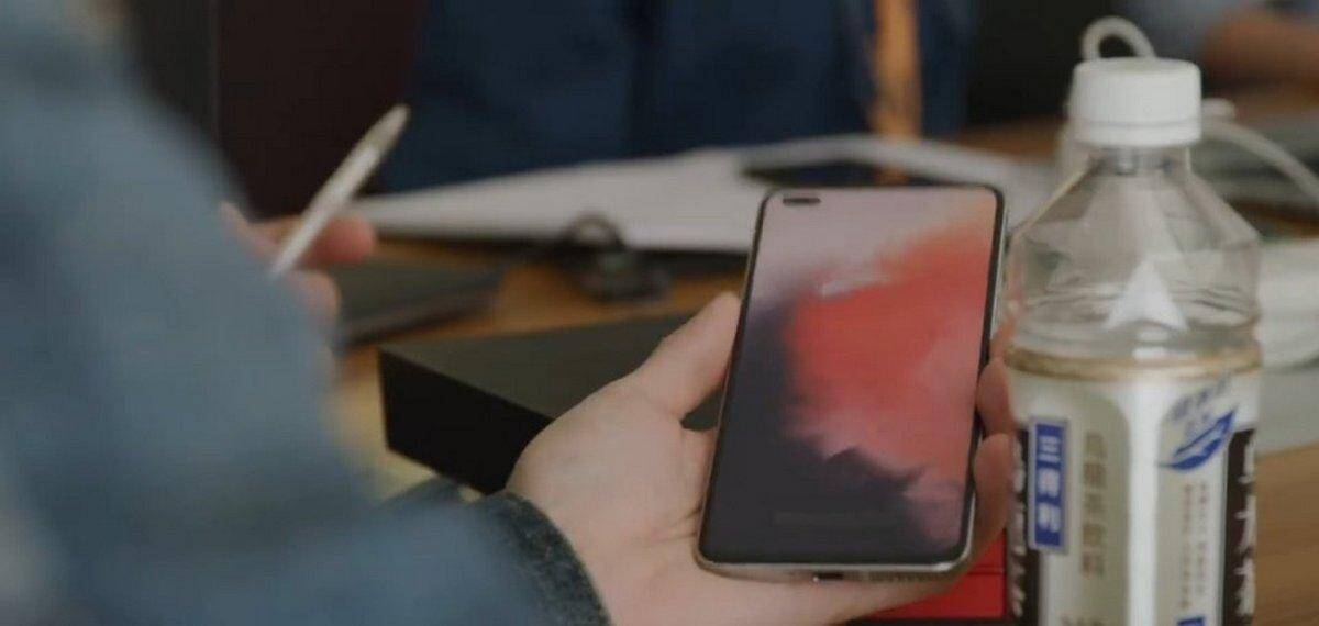 Смартфон OnePlus Nord в руке на столе