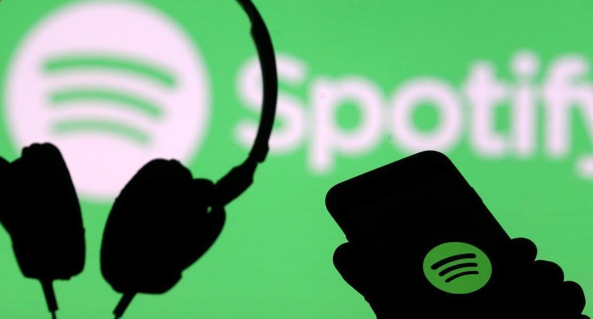 Черные наушники и смартфон с логотипом Spotify на фоне зеленого экрана