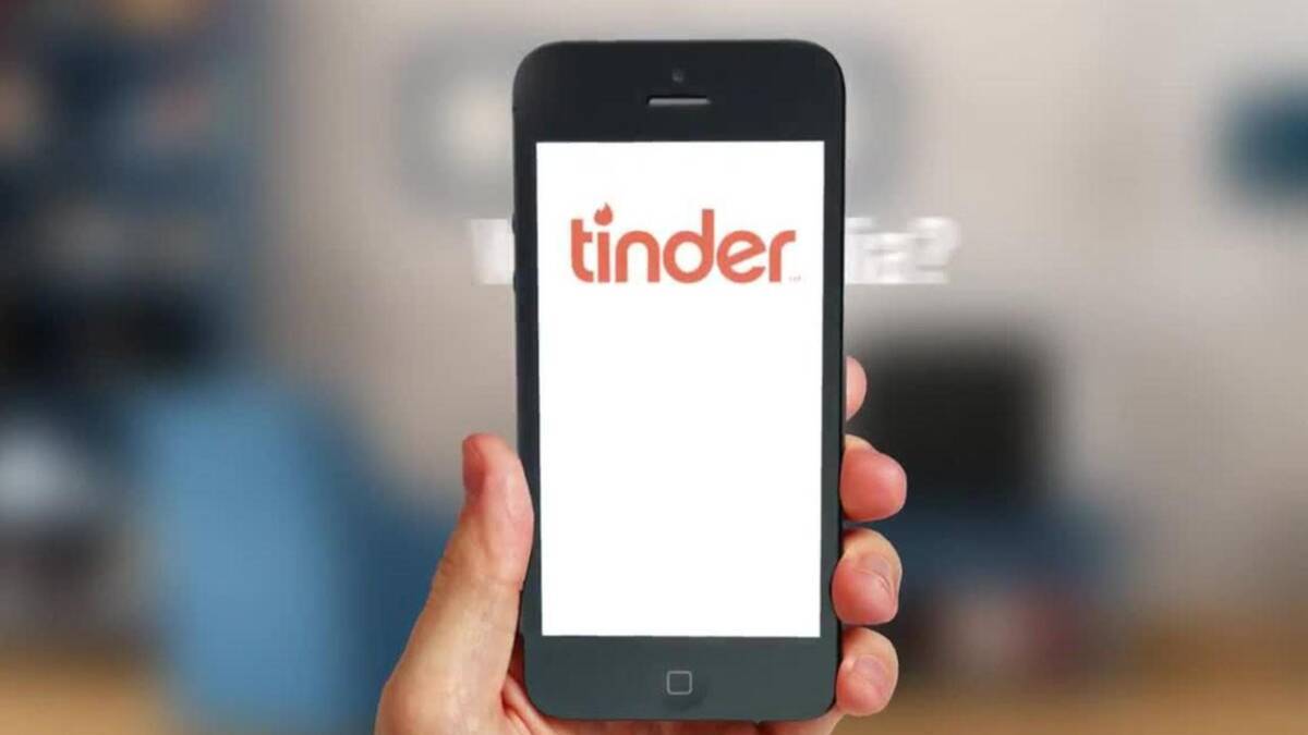 Рука держит смартфон с логотипом Tinder на экране