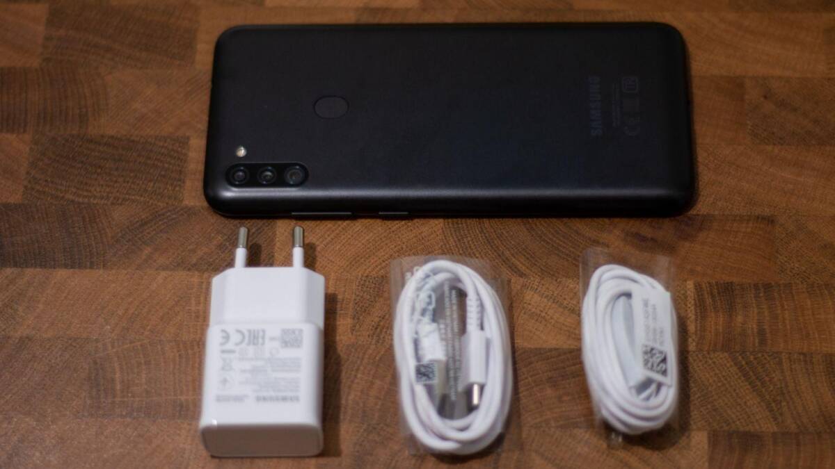 Обзор Samsung Galaxy M11. Народный смартфон 30 Черный смартфон Samsung Galaxy с тремя камерами на задней панели документы в руке