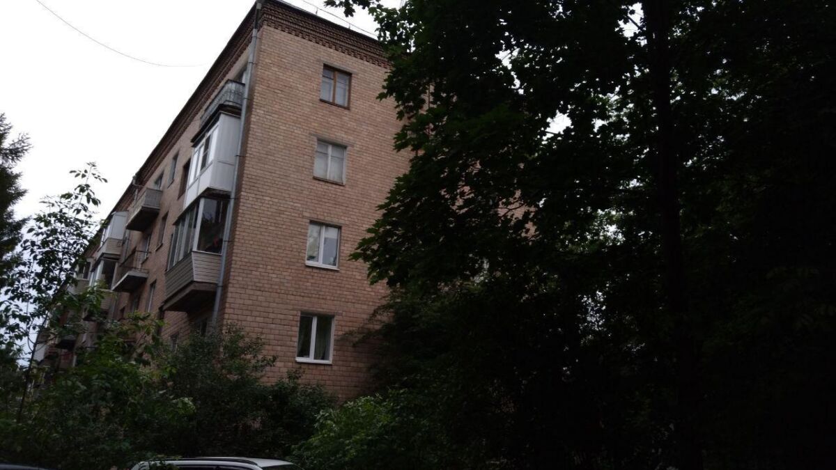 Фасад жилого многоквартирного дома на фоне деревьев