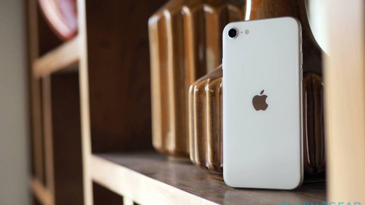 Белый iPhone SE 2020 стоит на деревянных полках