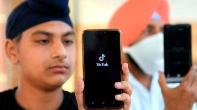 Два человека держат смартфоны с запущенными приложениями TikTok и YouTube в руках
