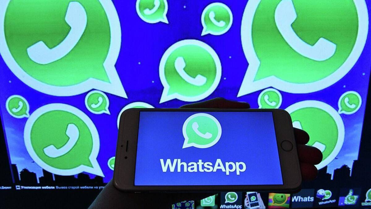 Смартфон с экраном, отображающим логотип WhatsApp на фоне